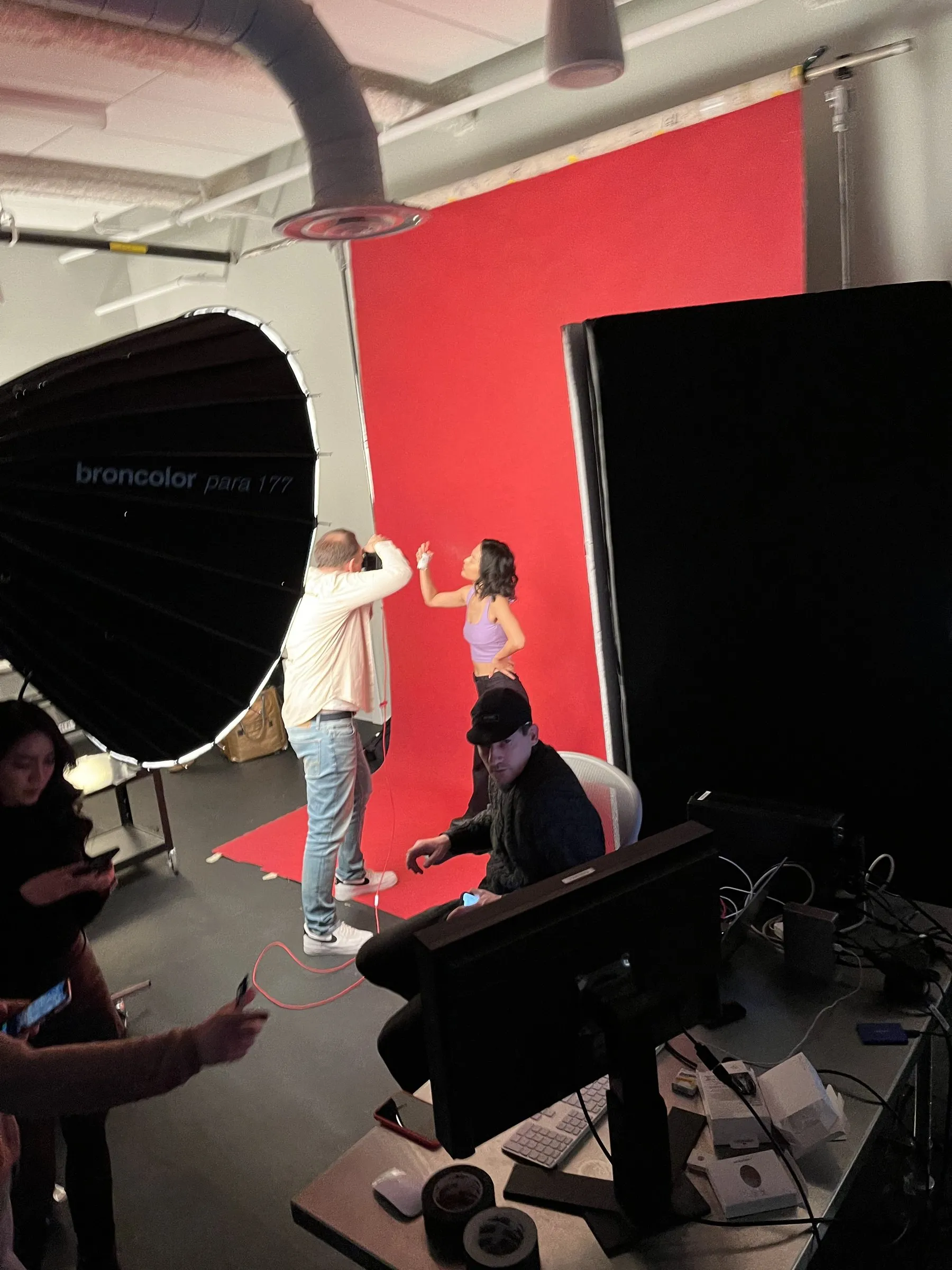 A shoot on a red backdrop with a broncolor Para reflector, the crew at monitors in the foreground.
