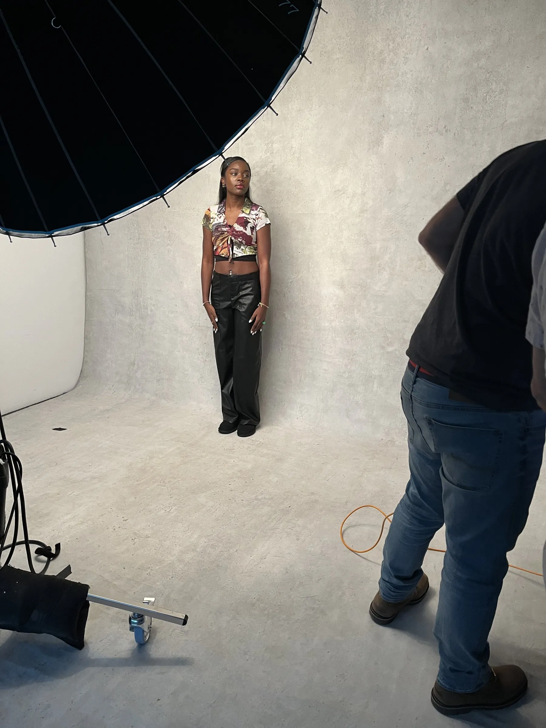 A portrait session in progress on a grey backdrop under a large umbrella light.