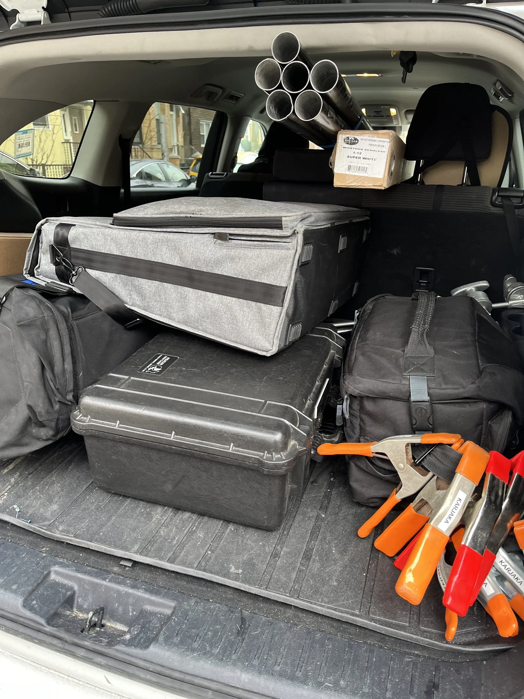 The back of a car packed for a location day: lighting cases, stands, sandbags and clamps.